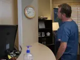 A nurse checks the time at his practice 